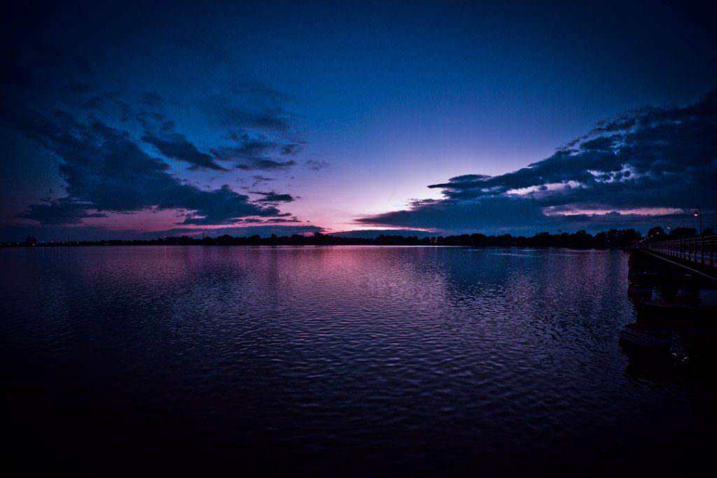 A sunset over Little Lake Butte Des Morts with dark water and clouds
